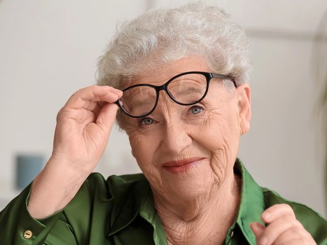 happy senior woman taking glasses off