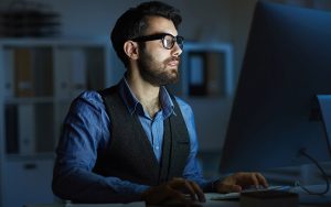 man working on his computer with low light
