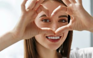 woman smiling with a hand heart