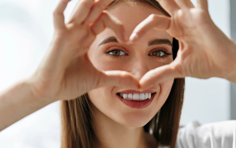 woman smiling with a hand heart