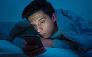 young man using his phone at night in bed