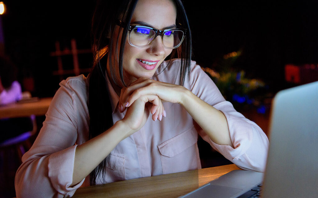 Smiling businesswoman in glasses looking at laptop