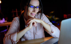 Smiling businesswoman in glasses looking at laptop