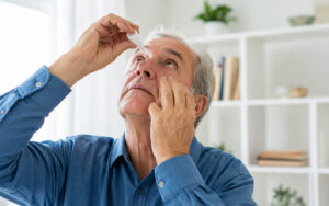 man doing eye drops at home